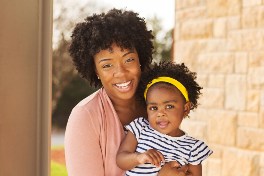 Mãe e filha pequena sorrindo para foto