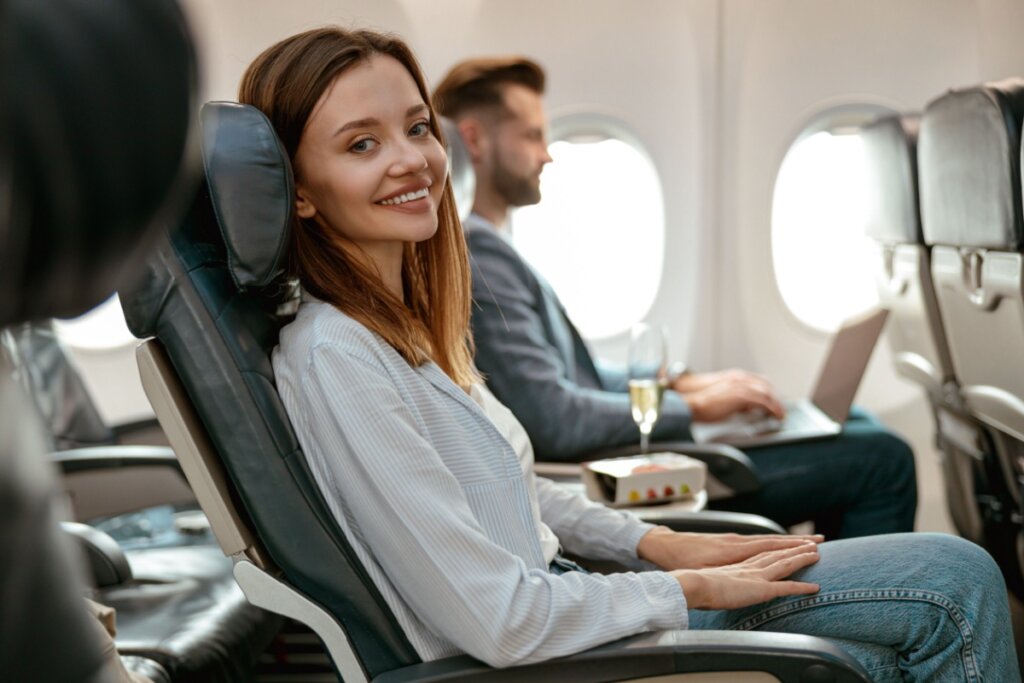 Mulher sentada em poltrona de avião e sorrindo