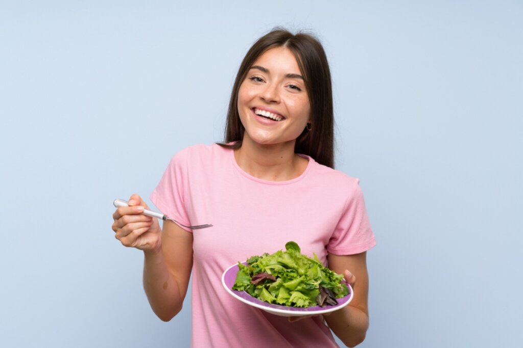 Mulher segurando prato com salada de folhas verdes