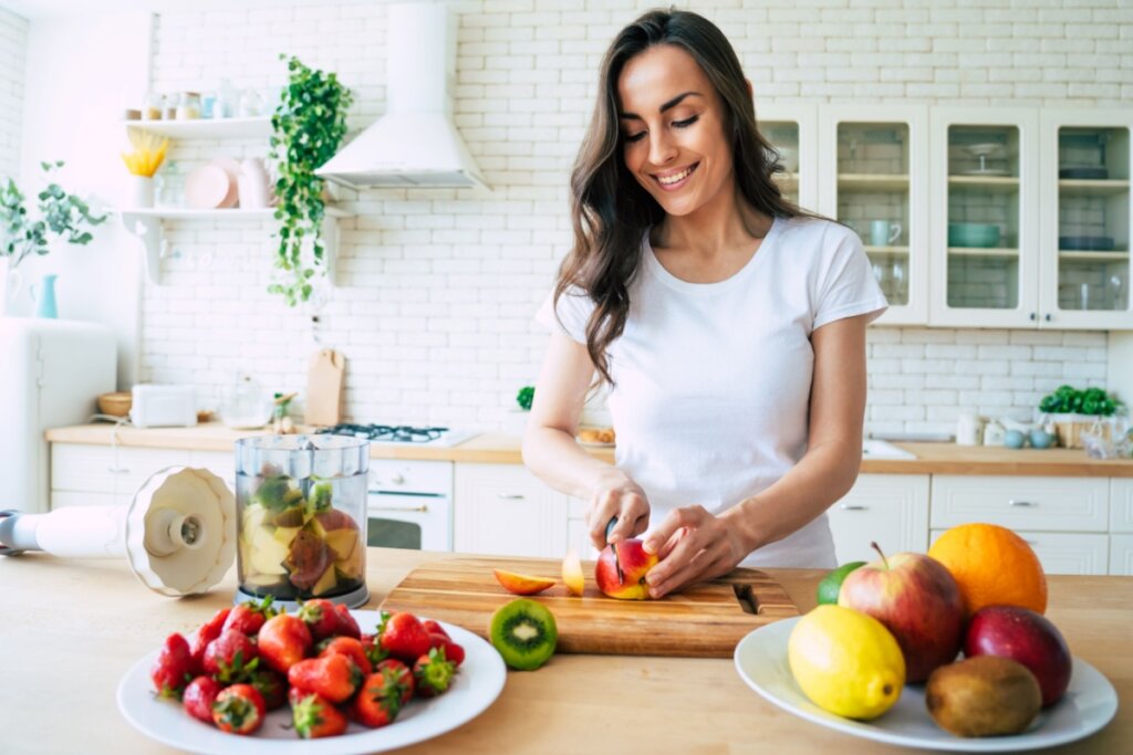 Mulher na cozinha cortando fruta em bancada