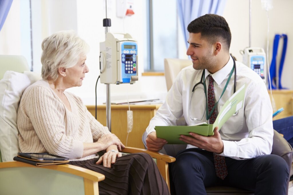 Paciente sentada fazendo quimioterapia e conversando com médico