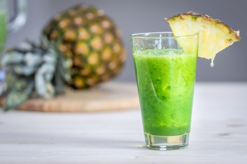 Suco verde em copo de vidro com fatia de abacaxi na borda