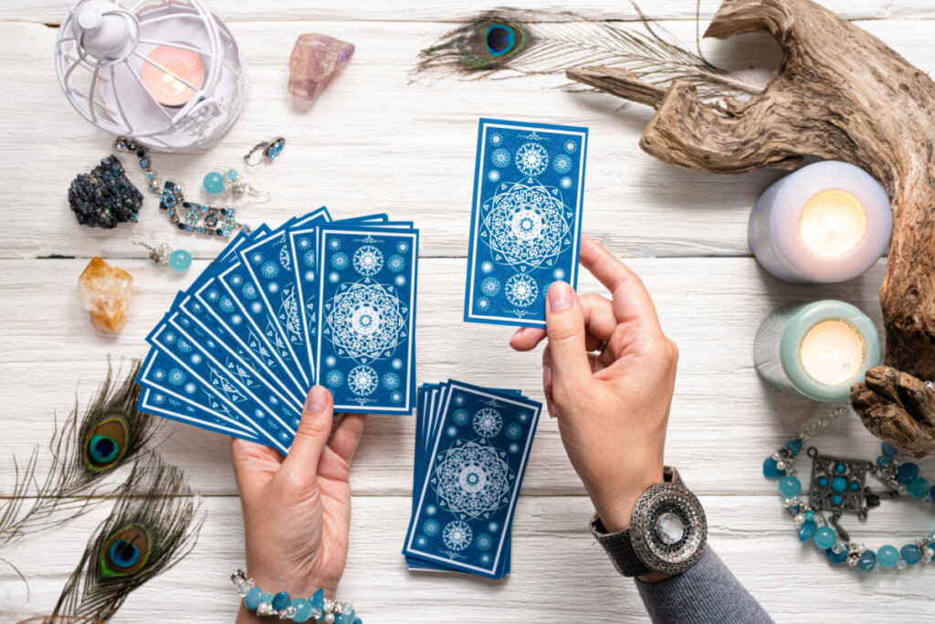 Mãos femininas segurando cartas de tarô azuis