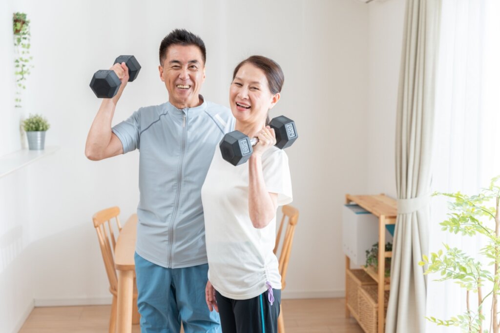 Mulher e homem asiáticos idosos em casa levantando peso.