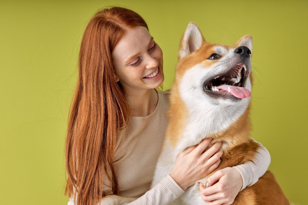 Mulher ruiva sorrindo abraçando cachorro
