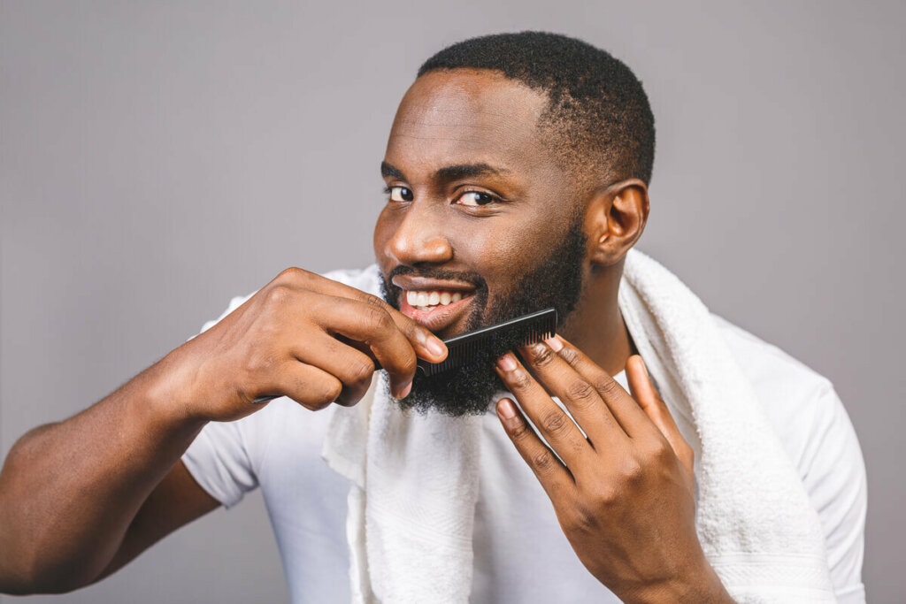 Homem sorrindo penteando a barba