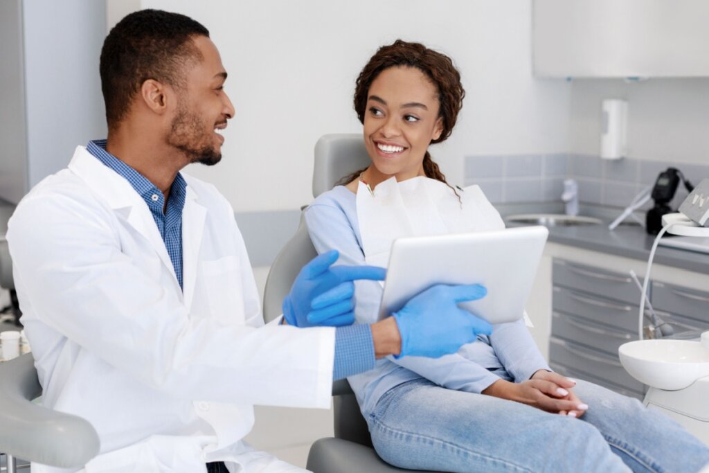 Dentista mostrando tablet para paciente sentada em cadeira