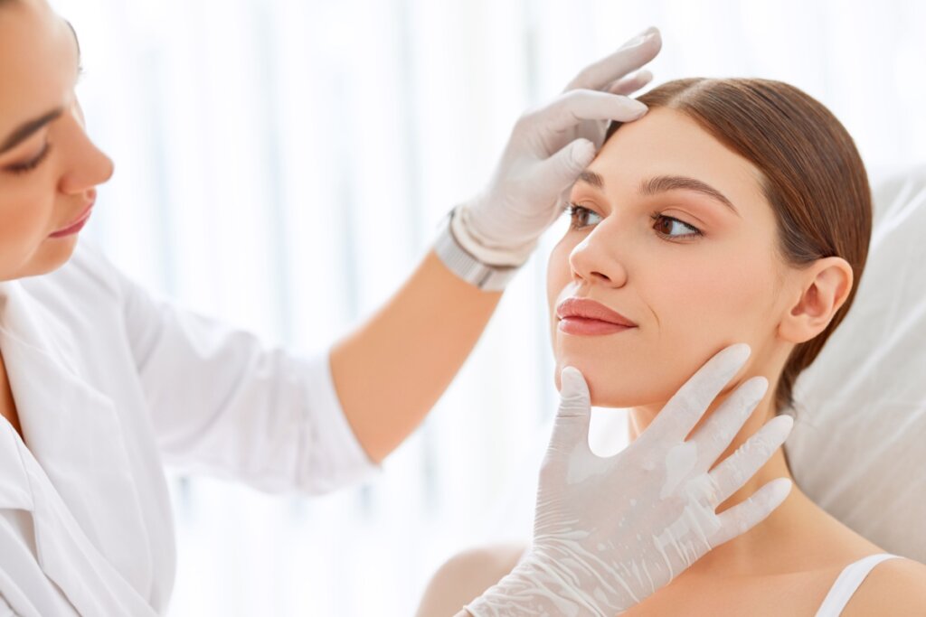 Dermatologista examinando rosto de jovem mulher.