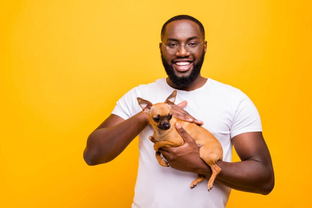 Homem sorrindo segurando cachorro no colo