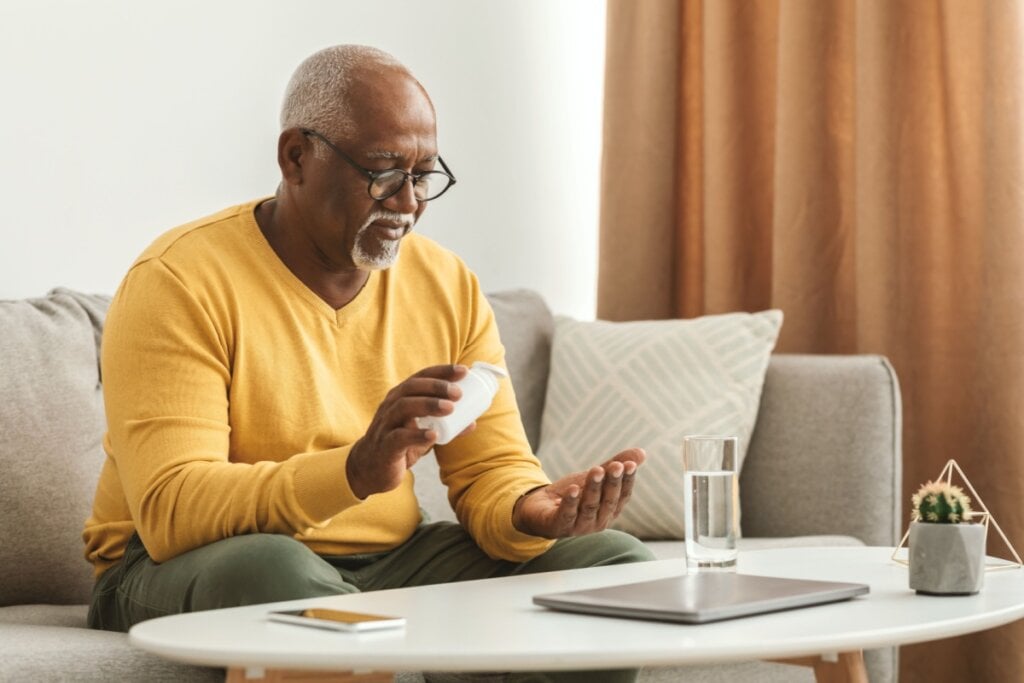 Homem sentado no sofá tomando remédio