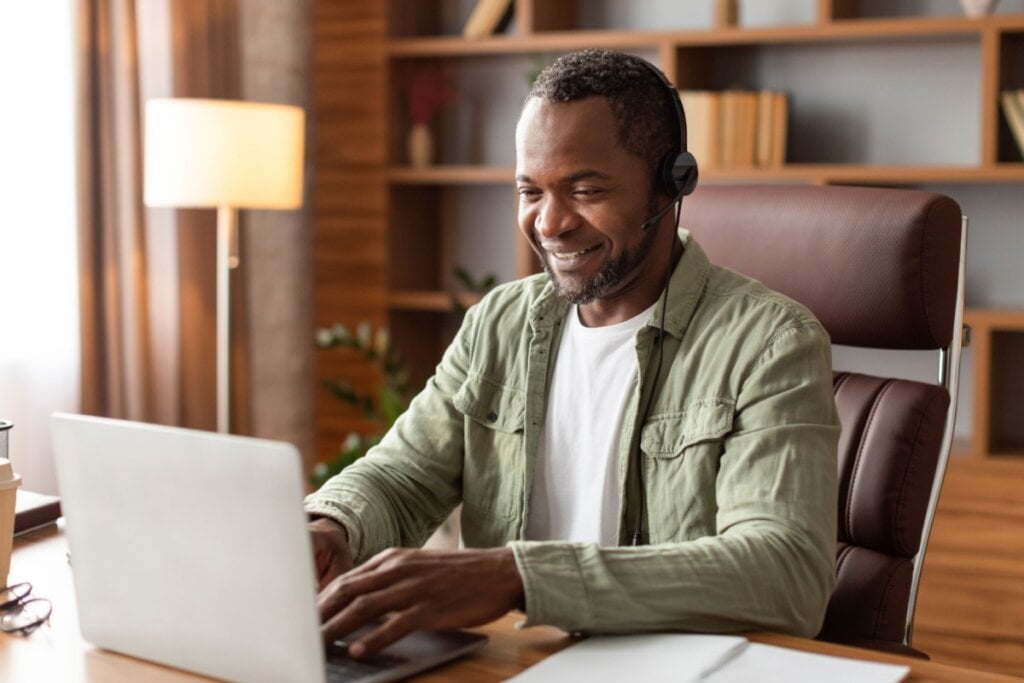 Homem sorrindo trabalhando de casa em computador