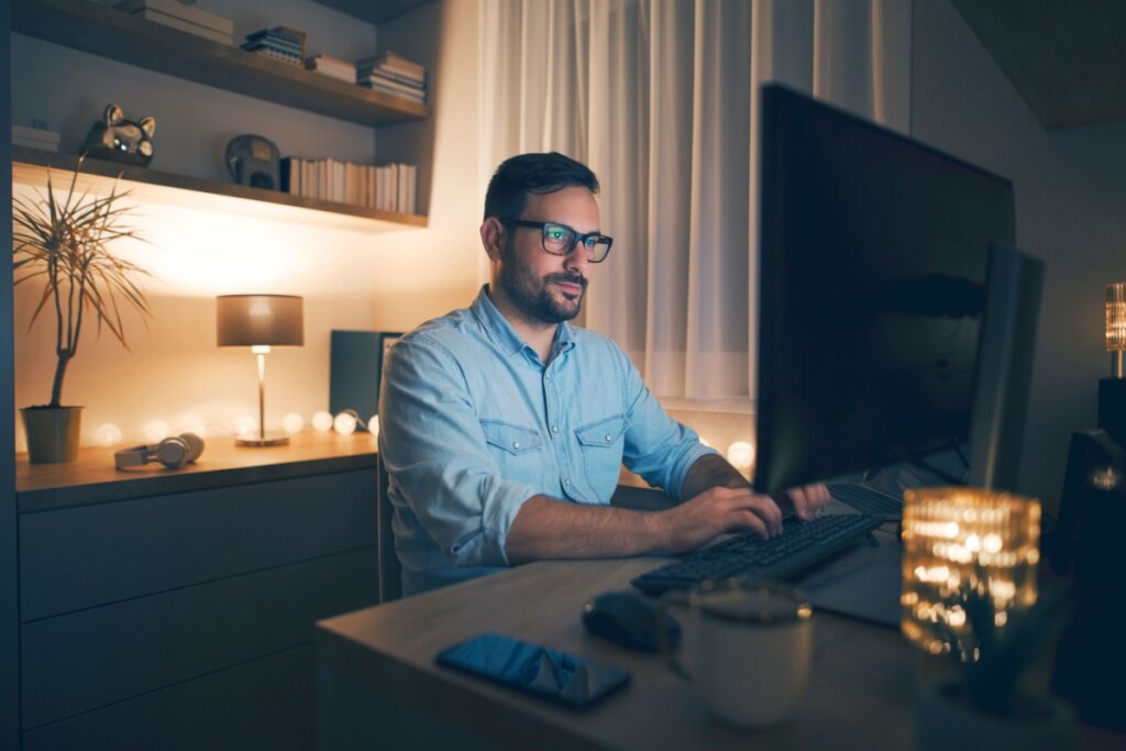 Homem de óculos usando computador em uma sala 