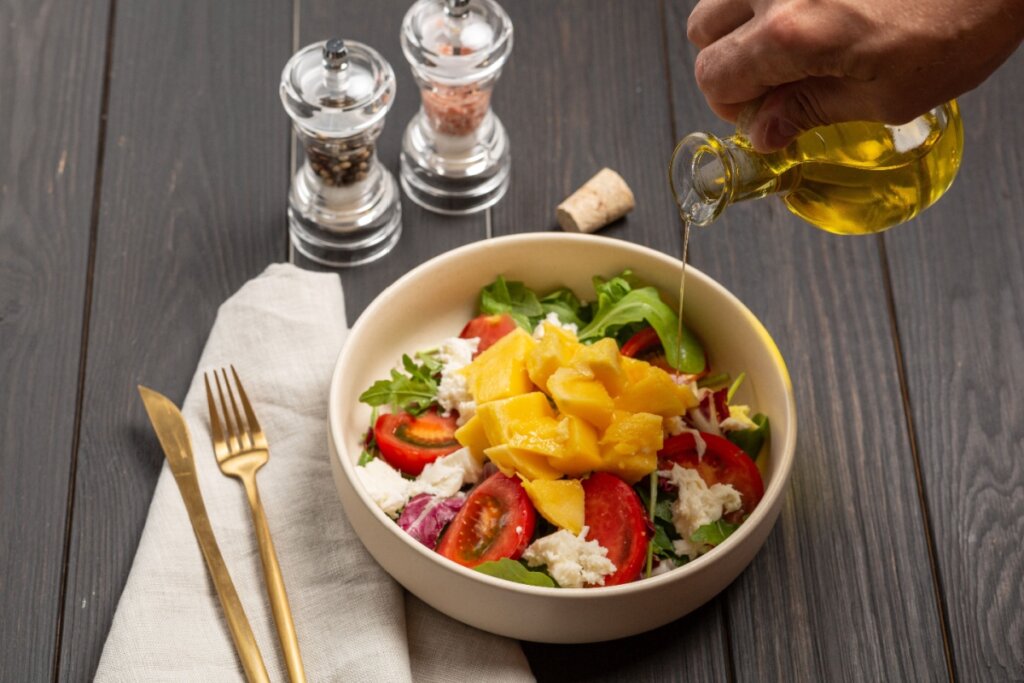 Recipiente com salada contendo rúcula, tomate, manga