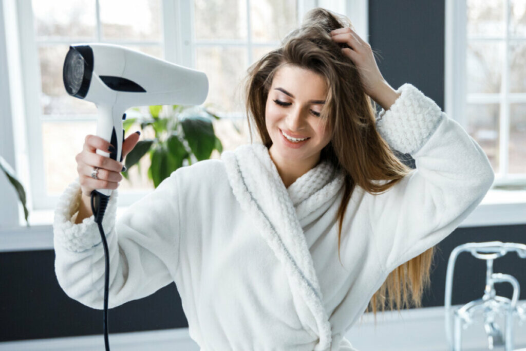 Mulher secando os cabelos com um secador 