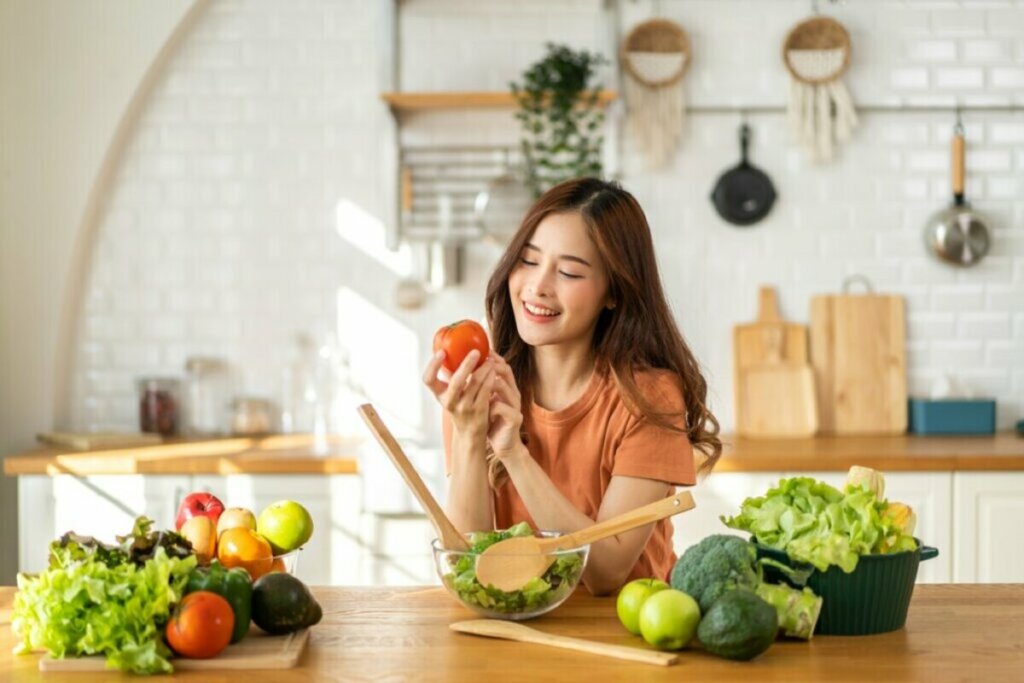 Mulher em uma cozinha segurando um tomate