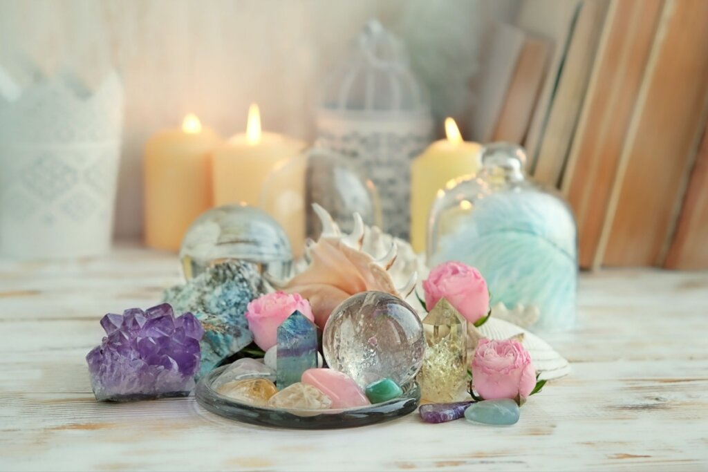 Cristales coloridos en una mesa con rosas y conchas.