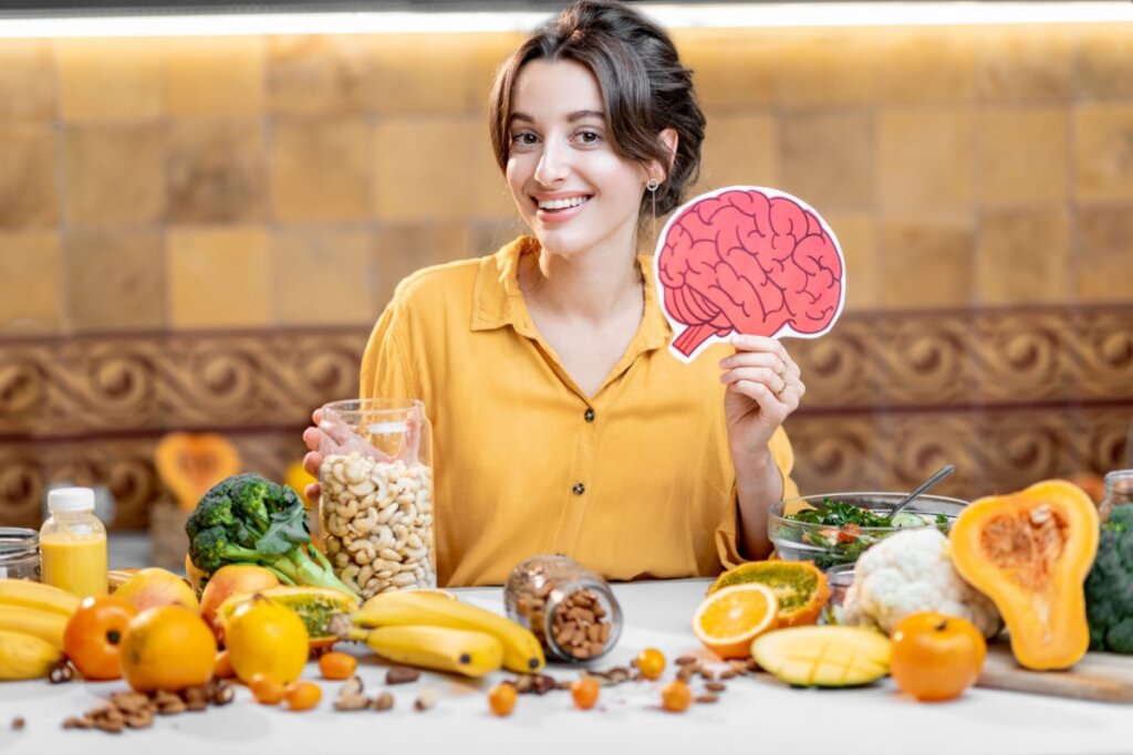 Alimentos segurando ilustração de um cérebro e com diversos alimentos a sua frente