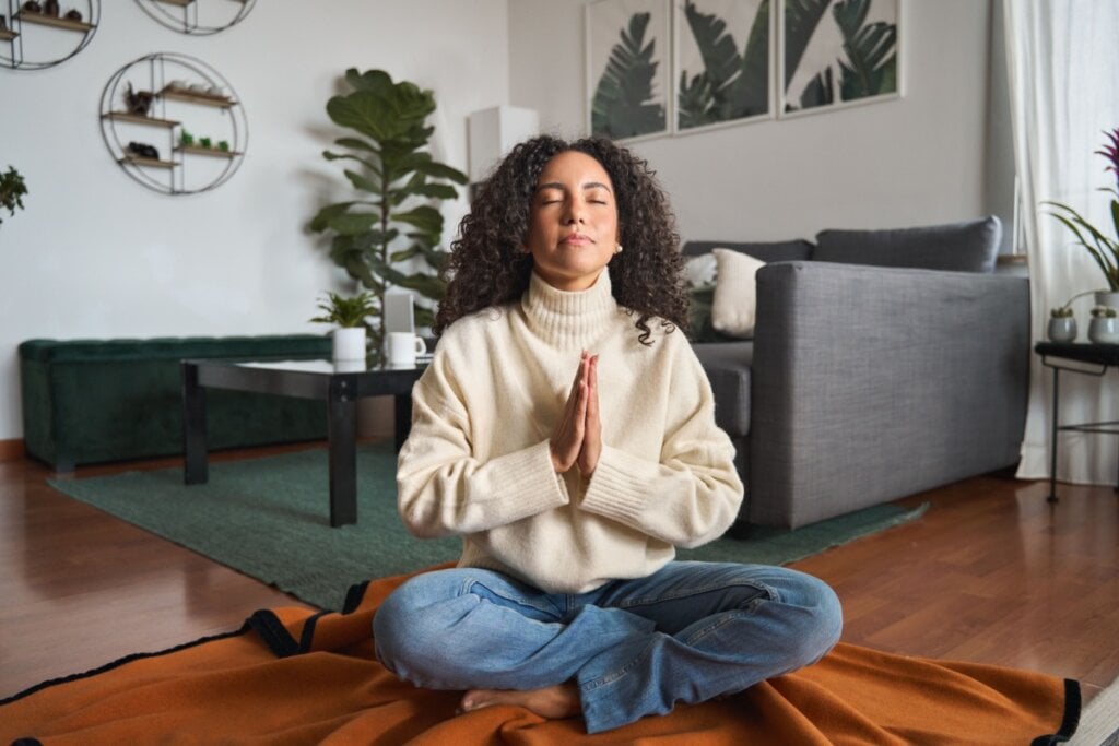 Mulher meditando com os olhos fechados e sentada no chão