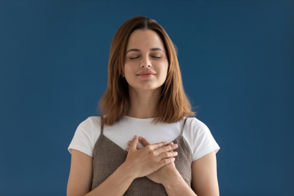 Mulher com os olhos fechados e a mãos no coração