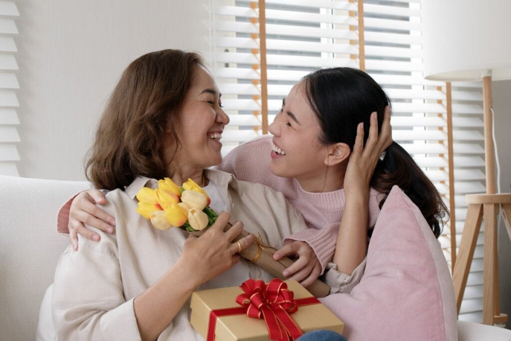 Mulher segurando um buquê de rosas e abraçando uma menina