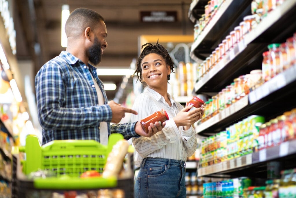 Homem e mulher em um supermercado olhando o rótulo de um produto