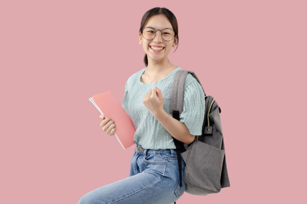 Estudante feliz com mochila nas costas segurando livros