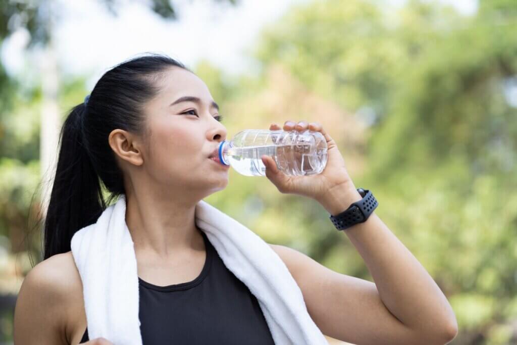 Mulher bebendo água em garrafa transparente