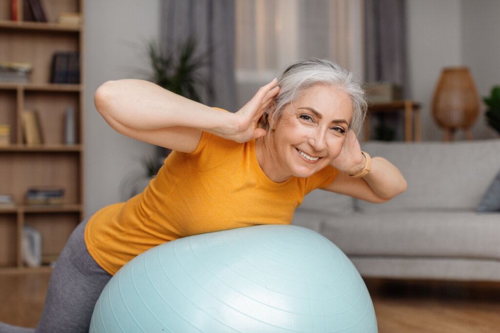 Mulher sorrindo fazendo exercício com bola suíça