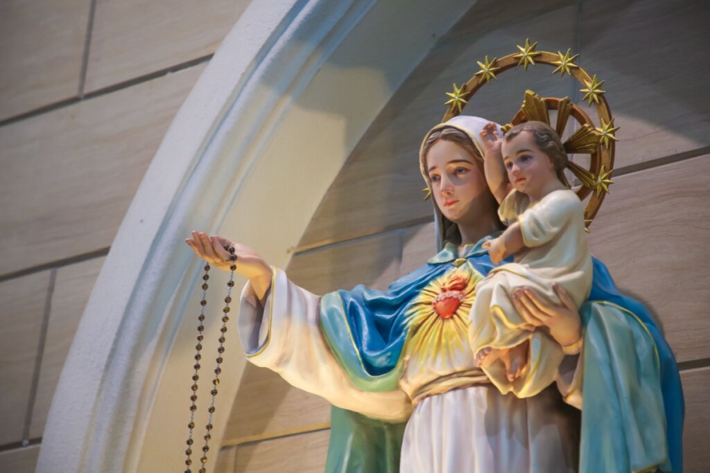 Imagem da Nossa Senhora Auxiliadora segurando o menino Jesus em um braço e com o outro braço esticado com um terço