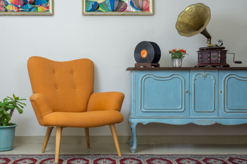 Interior vintage de poltrona laranja retro, aparador azul claro de madeira vintage, fonógrafo antigo (gramofone), registros de vinil no fundo da parede bege, piso de porcelana azulejos e tapete vermelho