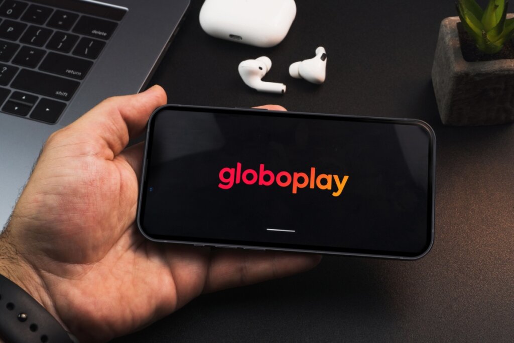 pessoa segurando um celular e na tela aparece o logo do streaming globoplay