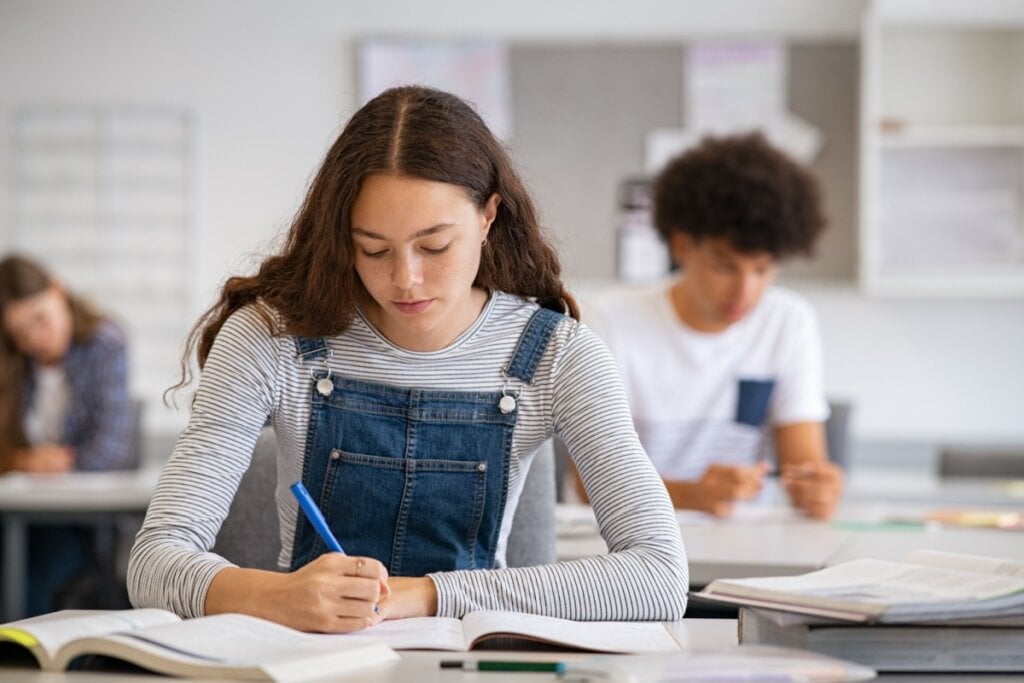 Menina sentada e escrevendo em caderno