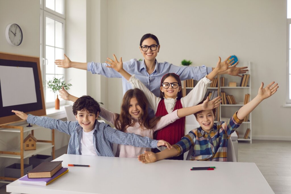 Professora com seus alunos de braços abertos