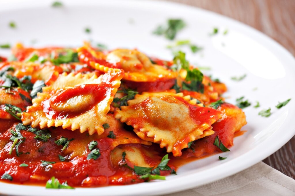 Ravioli com molho de tomate e manjericão em prato branco