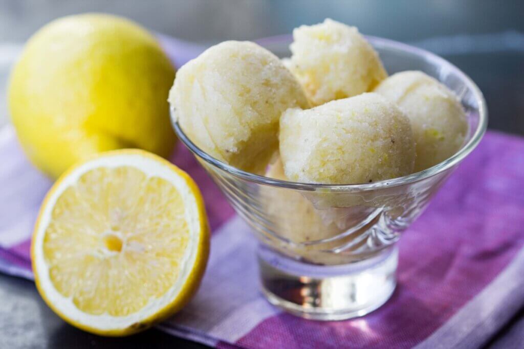 sorvete de limão em uma taça de vidro e com limões ao lado