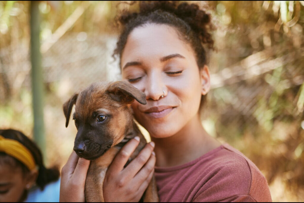 Mulher abraçando um filhote de cachorro com os olhos fechados