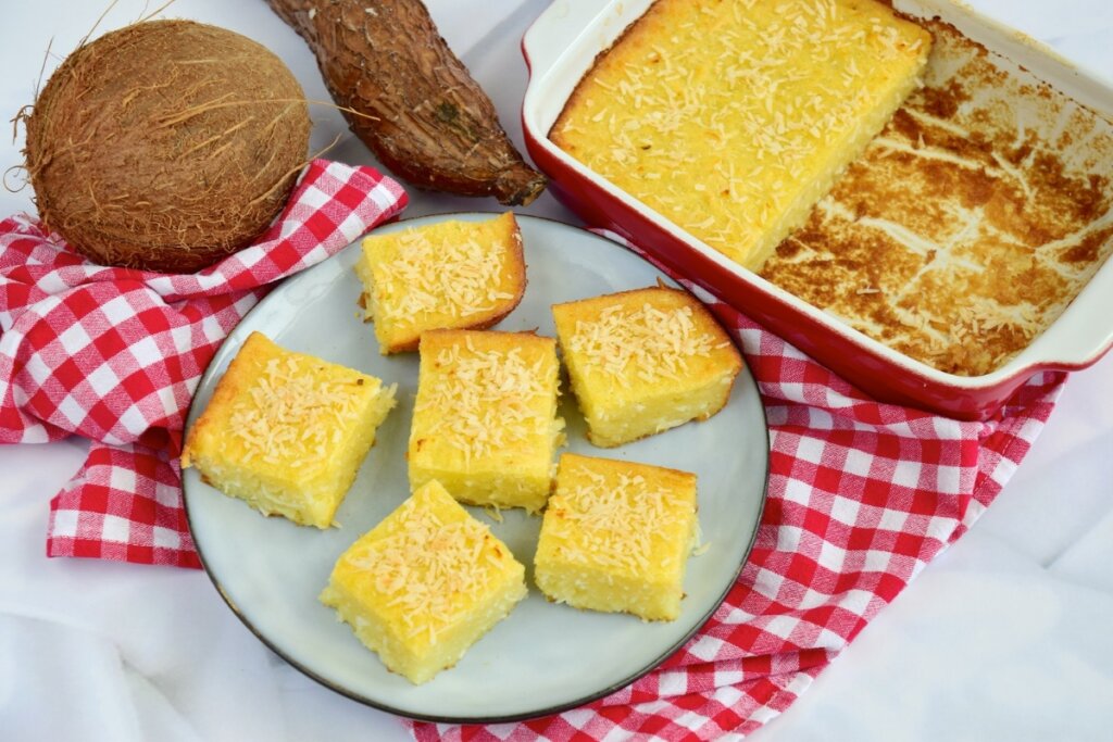 Bolo de mandioca em um prato branco em uma mesa branca com pano quadriculado