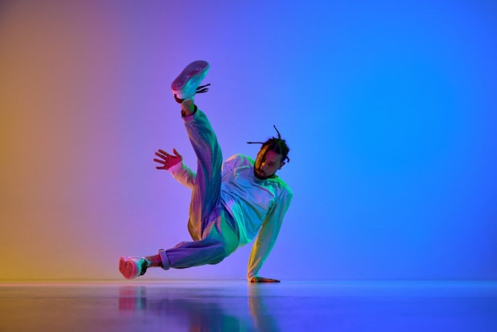 Homem em frente a um fundo colorido dançando breakdance 