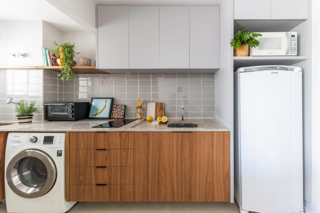 Cozinha com móveis de madeira, geladeira branca e uma máquina de lavar 