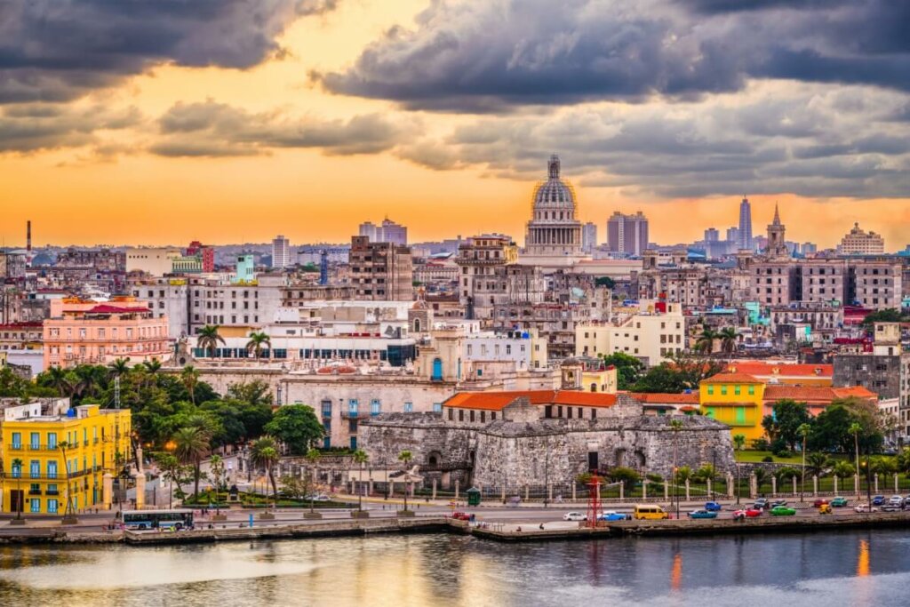Vista panorâmica de Havana, Cuba, destacando a arquitetura colonial colorida, o Capitólio de Havana ao fundo e árvores espalhadas pela cidade