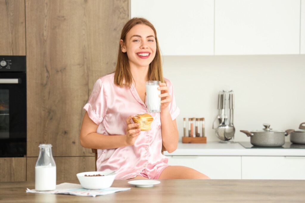 Mulher bebendo leite em cozinha