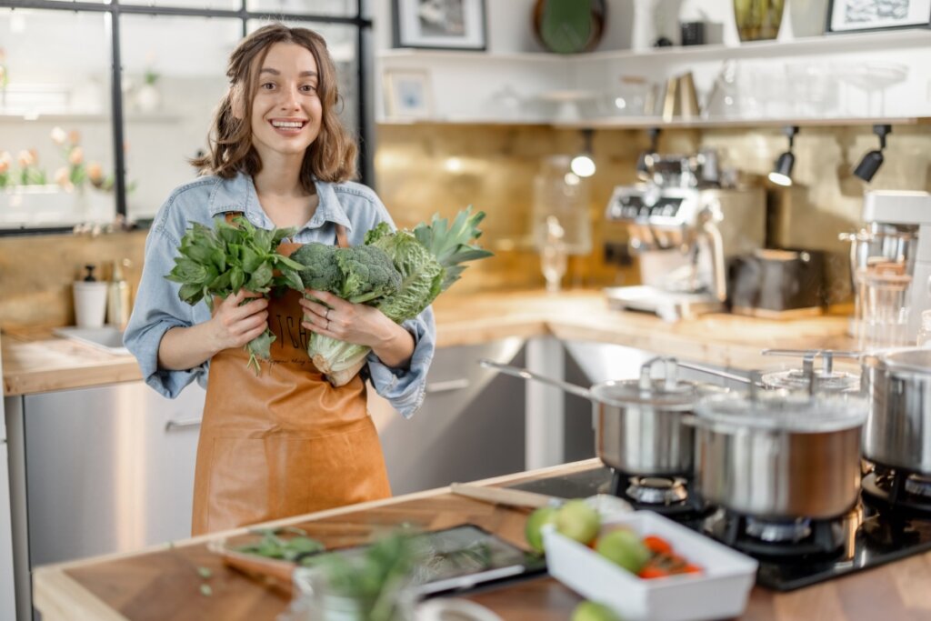 Mulher segurando verduras em cozinha