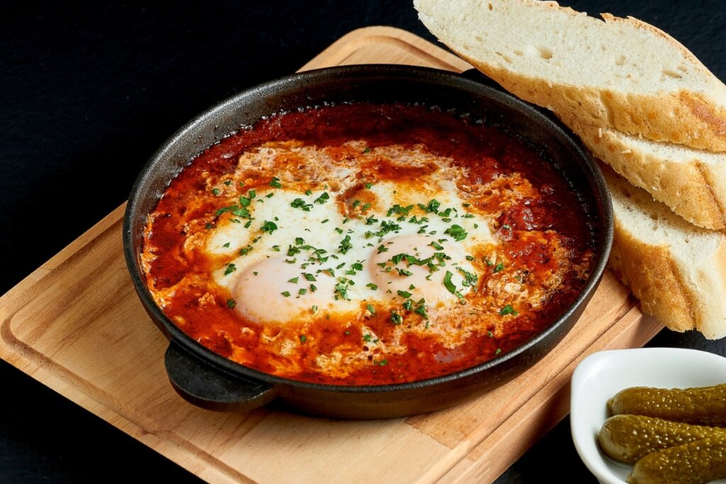 Ovo pochê com molho de tomate em uma frigideira preta