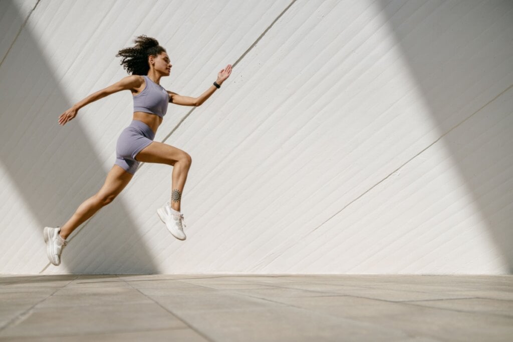 Atleta treinando salto vestindo roupas de academia. 