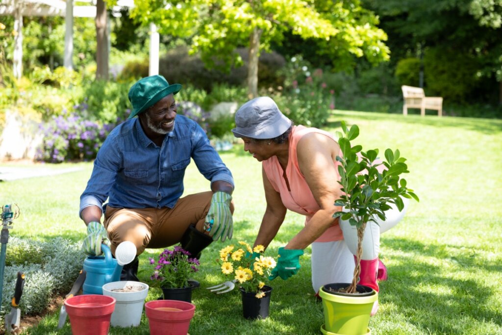 Casal em jardim abaixado no chão cuidando de plantas