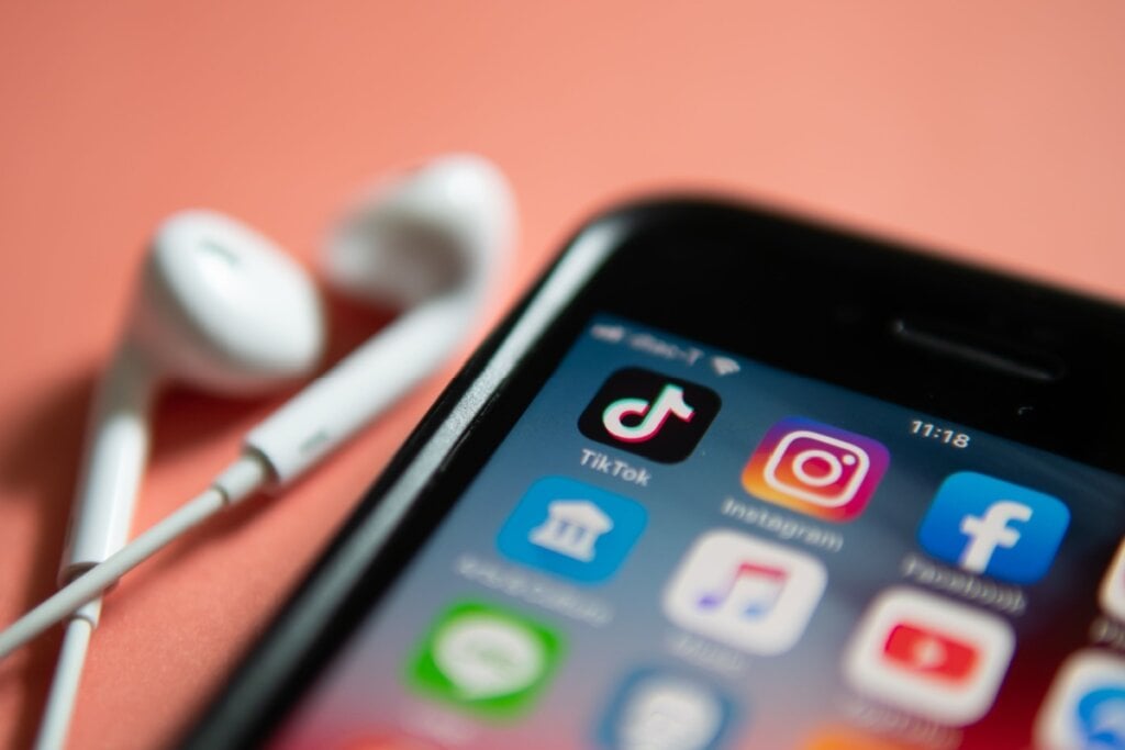 Celular preto com aplicativos de redes sociais como TikTok, Instagram e Facebook