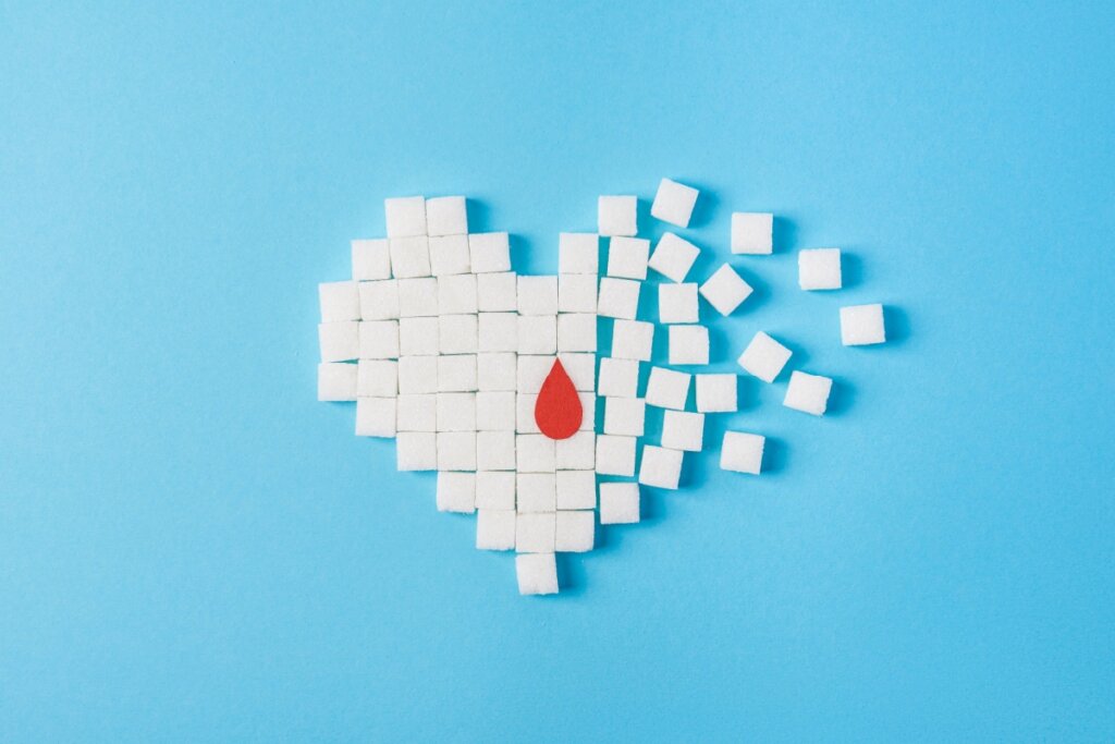 Coração formado por cubus de açúcar e com uma gota de sangue em cima em um fundo azul