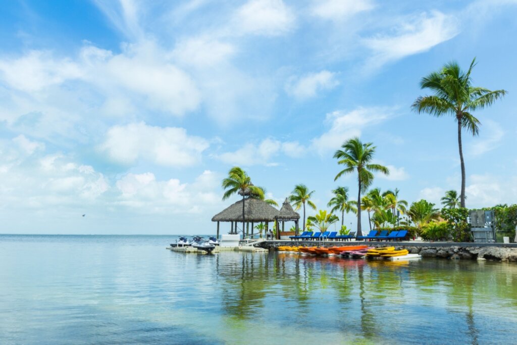 Paisagem de Key Largo na Florida, uma estação a beira-mar com cadeiras e jet skis. Ao fundo um céu azul limpo