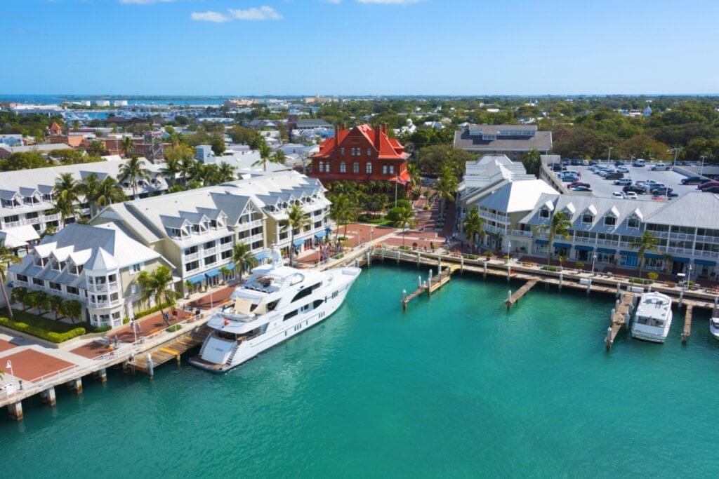 Vista de cima do porto de Key West na Florida, há um barco atracado e é possível ver as ruas com diversas lojas e comércios. 