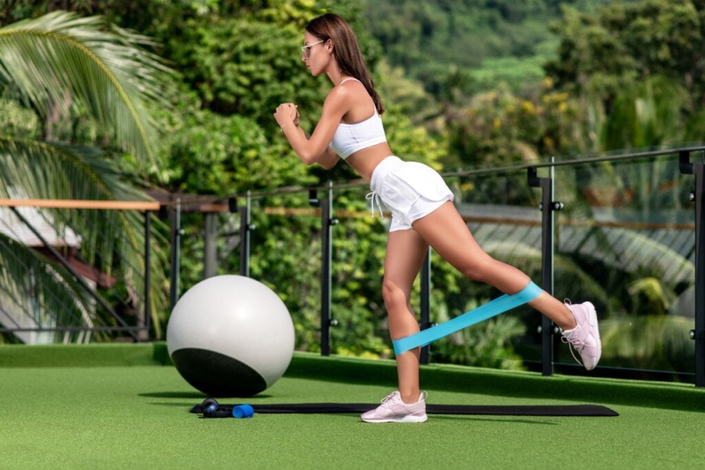 Mulher fazendo exercício para o glúteo com elástica na perna